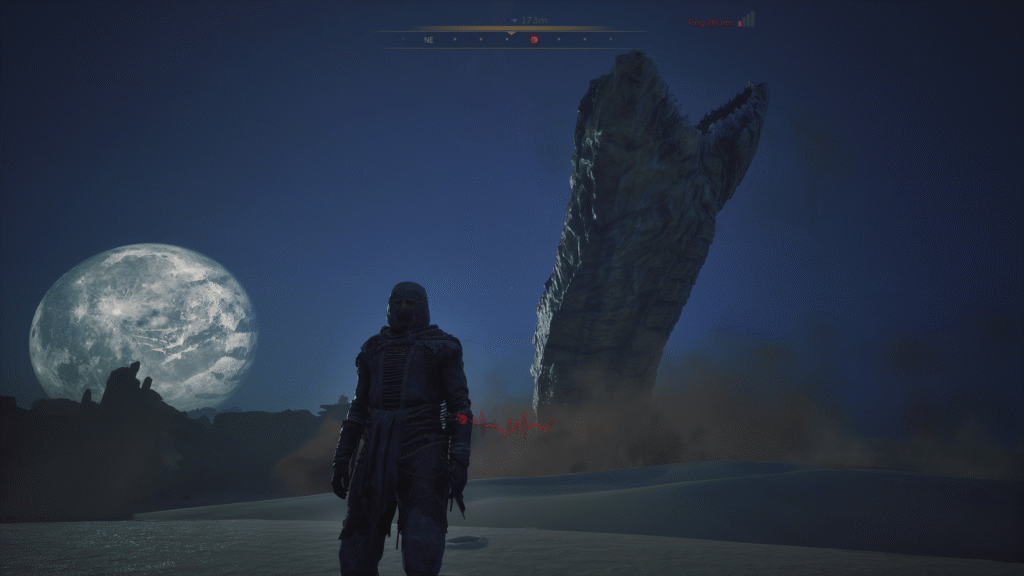 A player in a stillsuit stands before a massive sandworm erupting from the desert of Arrakis under a full moon.